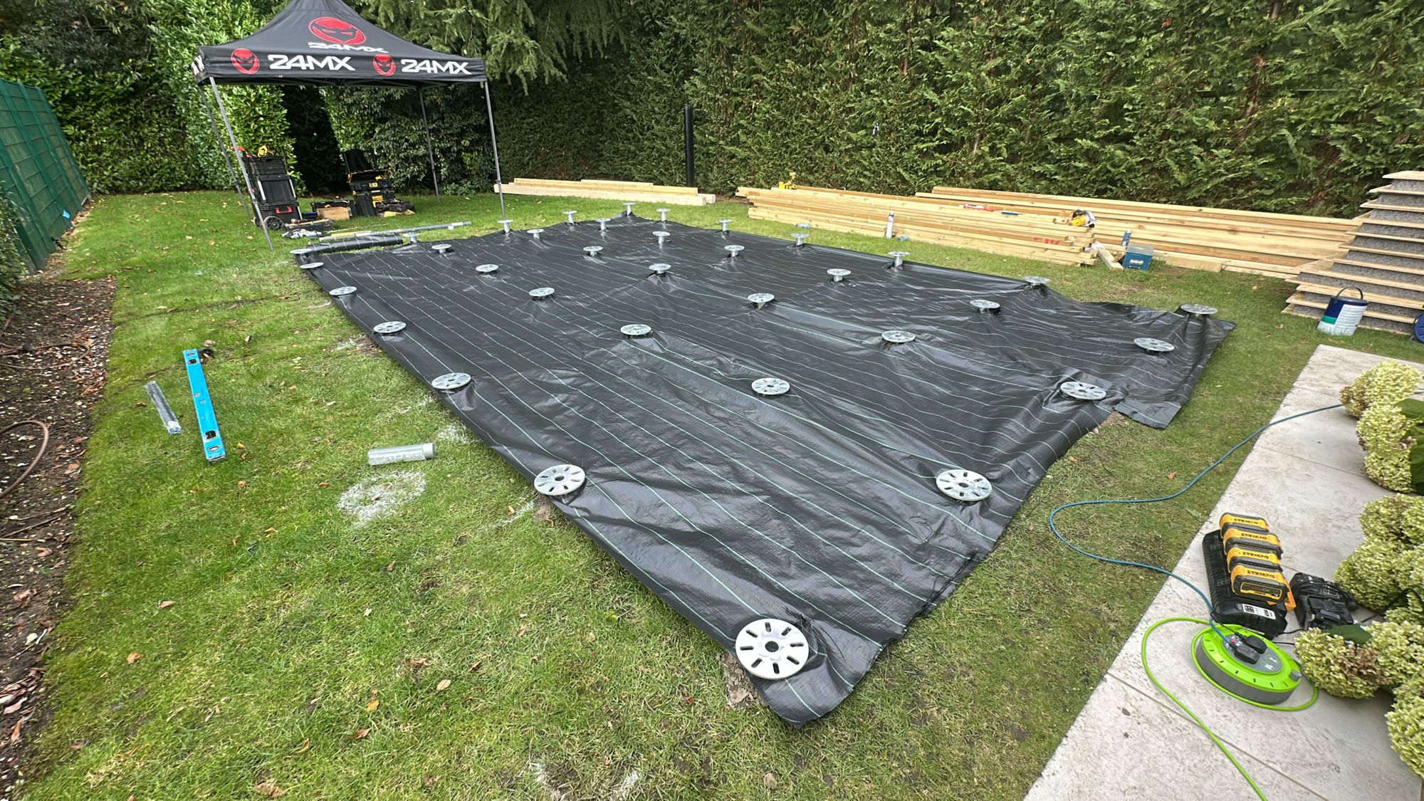 Completed ground screw foundation with membrane laid and timber stacked, ready for garden room construction