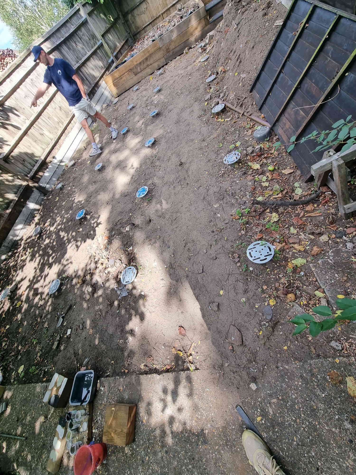 Installer working in a narrow garden with exposed soil