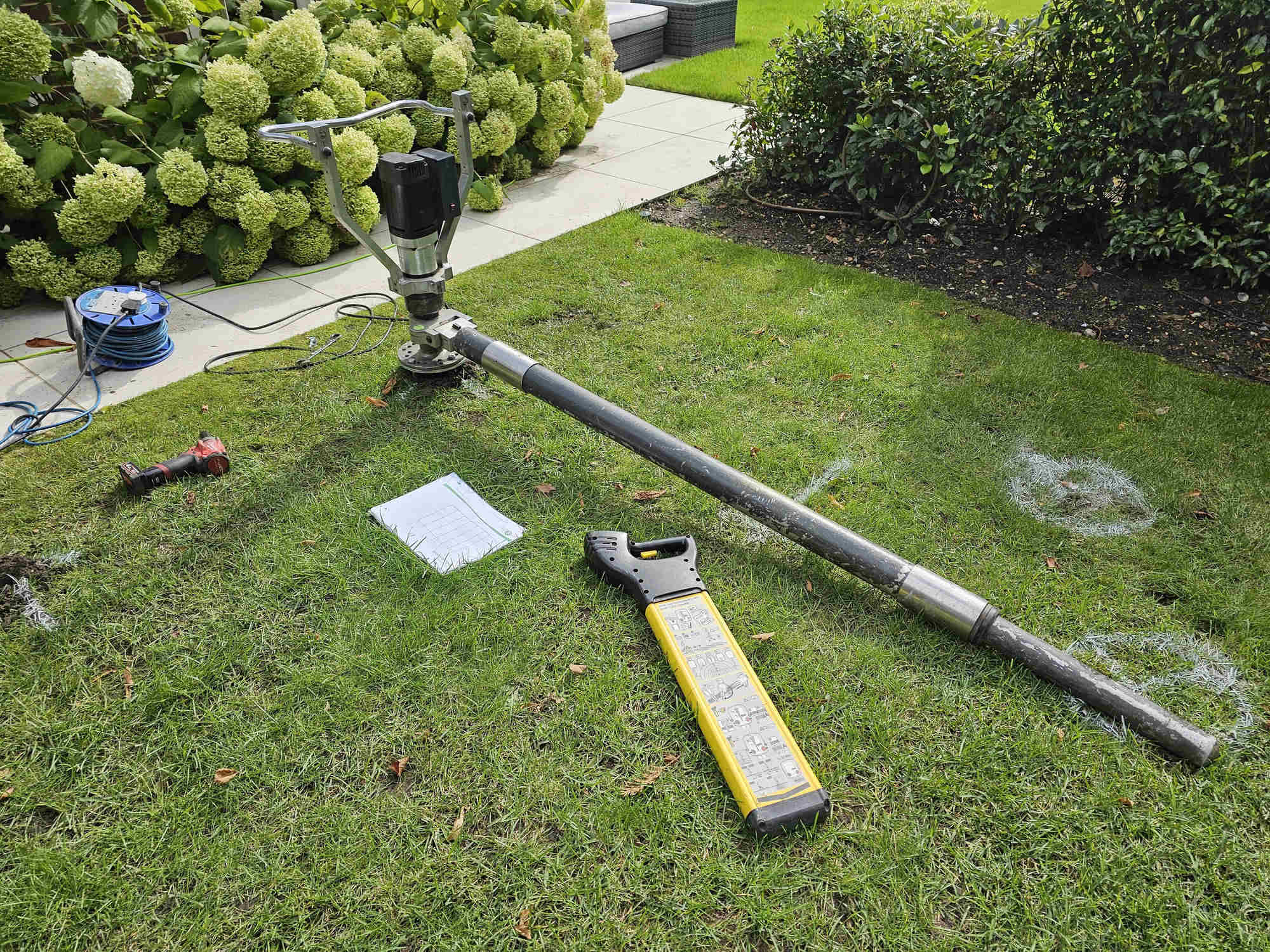 Ground screw installation and testing equipment set up on a garden lawn, ready for load test