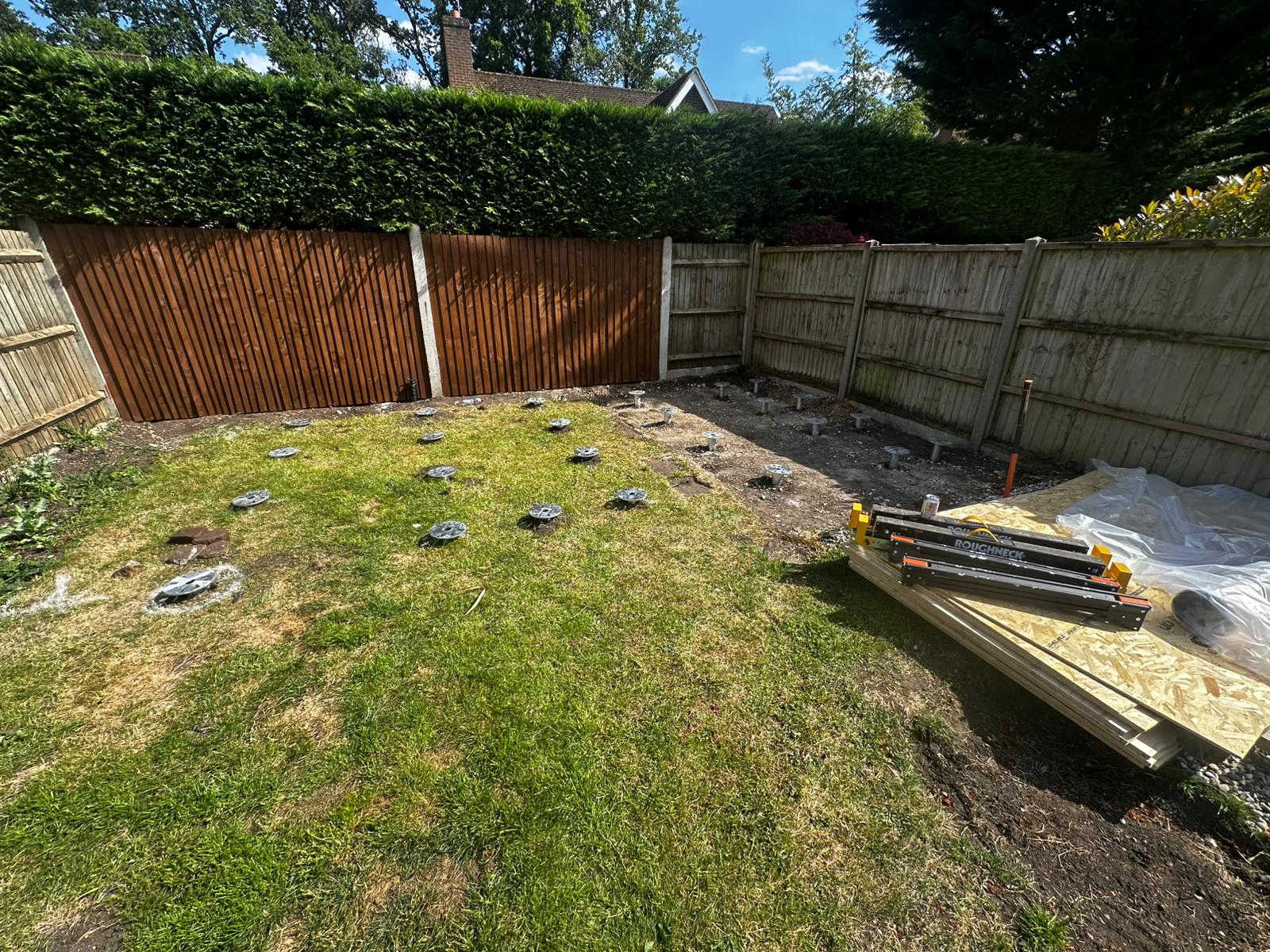 Grid of ground screws on a sunny lawn